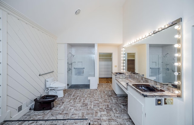 bathroom with vanity, toilet, a shower with door, and a bidet