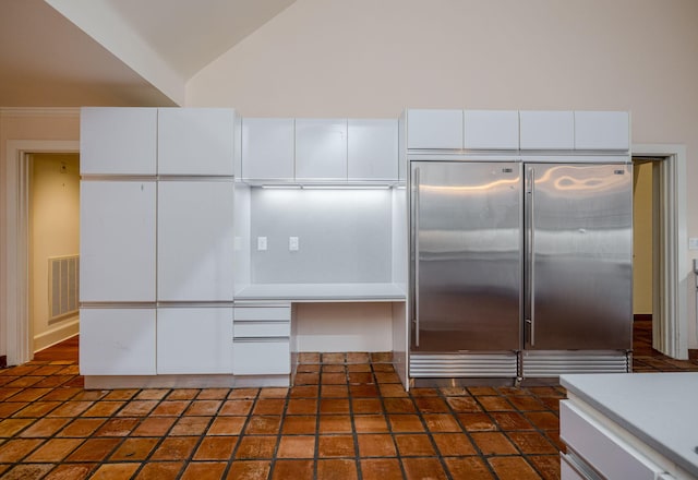 kitchen featuring white cabinetry, high end fridge, and lofted ceiling