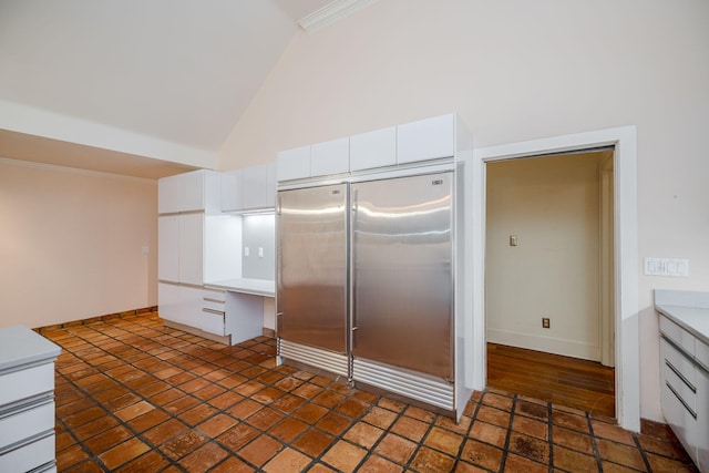 kitchen with stainless steel built in refrigerator, white cabinetry, and high vaulted ceiling