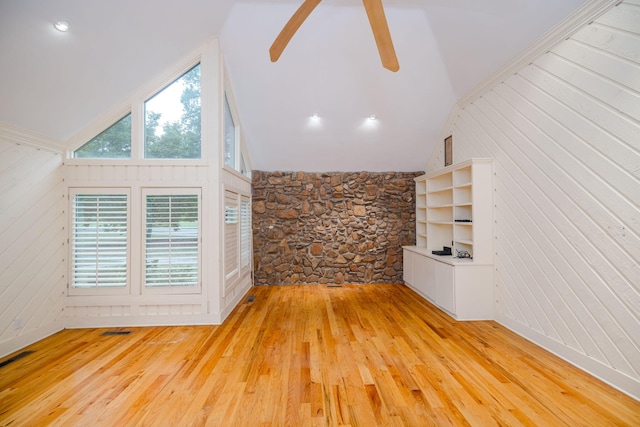 unfurnished living room featuring wooden walls, high vaulted ceiling, and light hardwood / wood-style floors