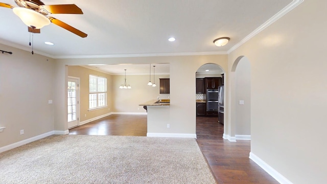 interior space with baseboards, arched walkways, a ceiling fan, and crown molding