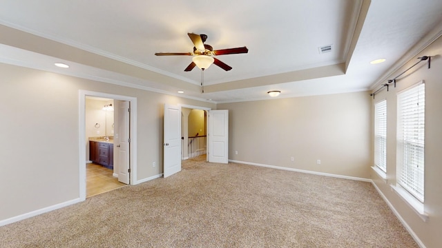 unfurnished bedroom with light carpet, visible vents, baseboards, a raised ceiling, and crown molding