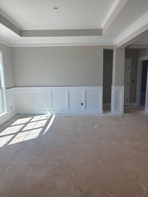 unfurnished room with a wainscoted wall, a tray ceiling, and a decorative wall