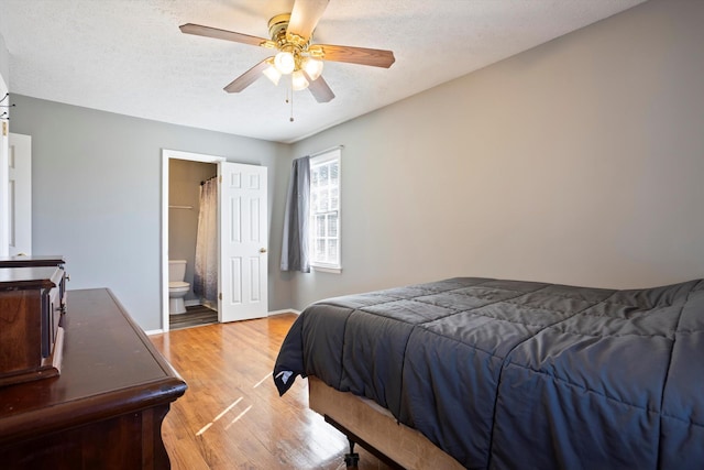 bedroom featuring ensuite bathroom, light wood-type flooring, a textured ceiling, and ceiling fan