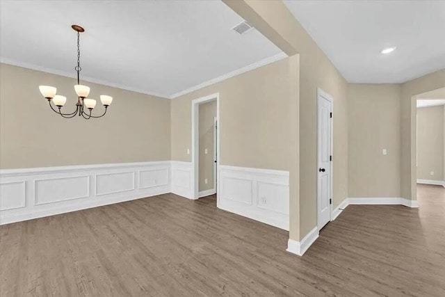 spare room with dark hardwood / wood-style floors, ornamental molding, and an inviting chandelier