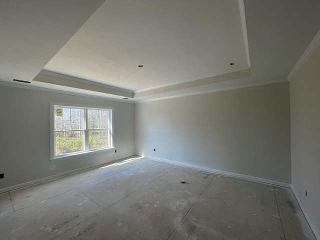 spare room with crown molding, a tray ceiling, and baseboards