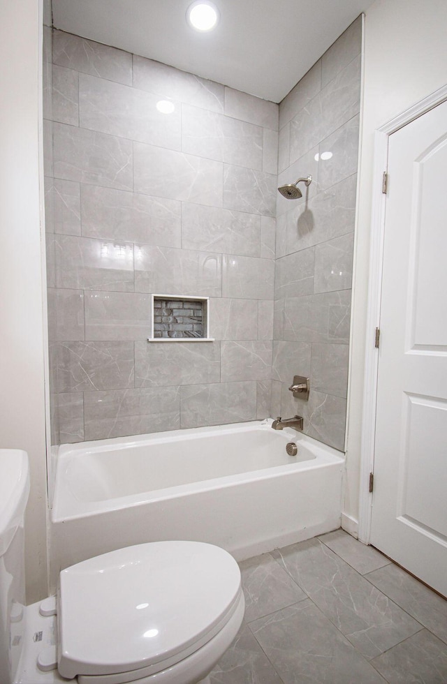 bathroom featuring toilet and tiled shower / bath