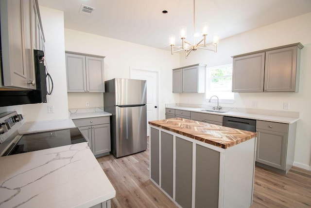 kitchen featuring appliances with stainless steel finishes, a center island, gray cabinets, and hanging light fixtures