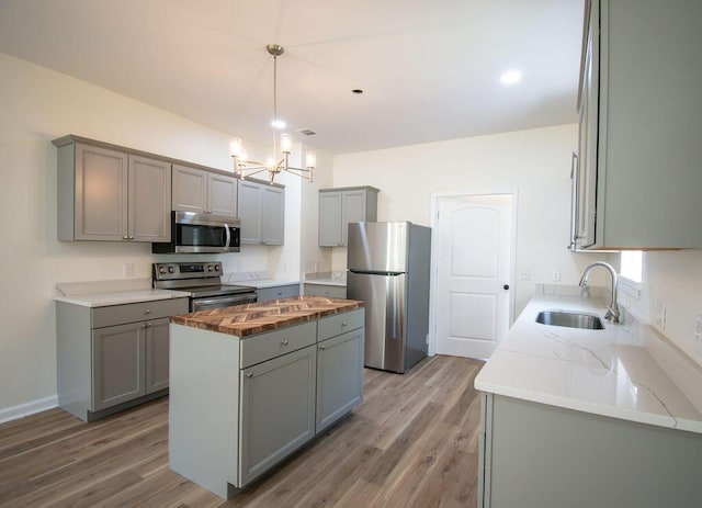 kitchen featuring a center island, gray cabinets, sink, and appliances with stainless steel finishes