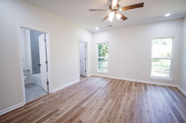 unfurnished bedroom with ensuite bathroom, ceiling fan, and light hardwood / wood-style flooring