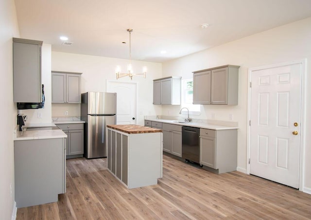 kitchen with hanging light fixtures, gray cabinets, a center island, and stainless steel appliances