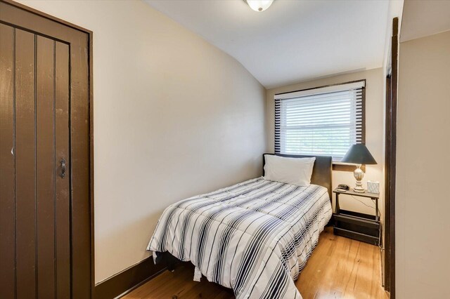 bedroom featuring a closet, light hardwood / wood-style floors, and lofted ceiling