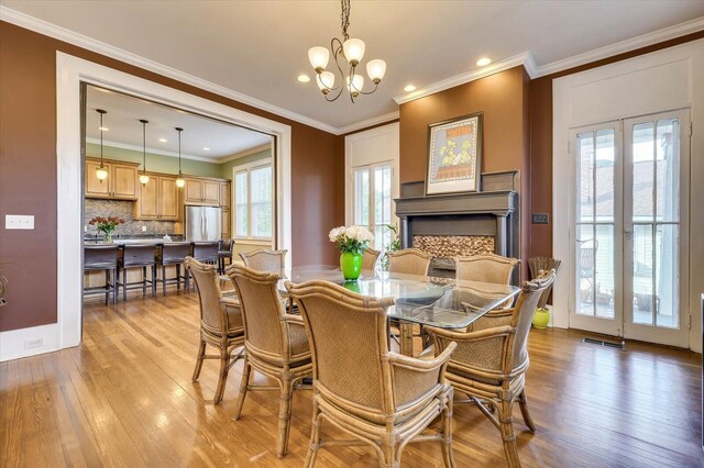 dining space featuring a notable chandelier, crown molding, a wealth of natural light, and light hardwood / wood-style flooring