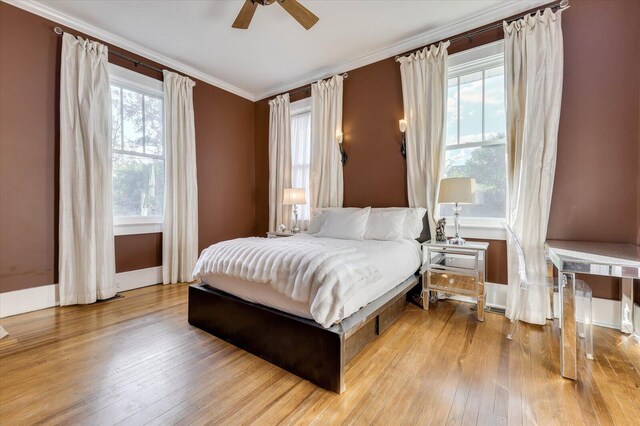 bedroom featuring multiple windows, ceiling fan, light hardwood / wood-style floors, and ornamental molding