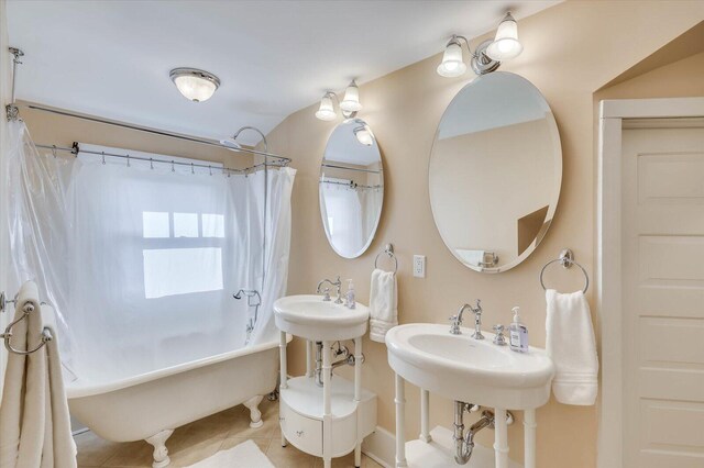 bathroom with tile patterned floors, shower / bath combo with shower curtain, and dual sinks