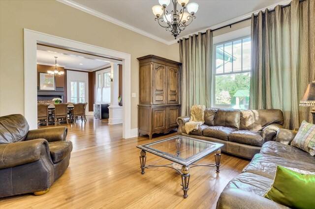 living room featuring light hardwood / wood-style floors, ornate columns, crown molding, and a chandelier