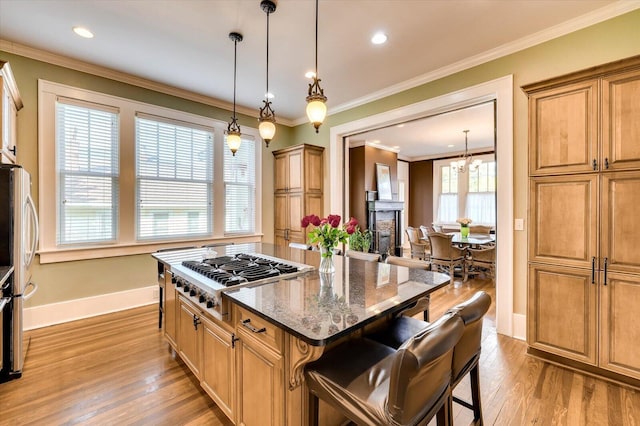 kitchen featuring a kitchen breakfast bar, appliances with stainless steel finishes, a wealth of natural light, dark stone counters, and a center island