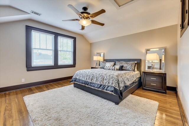 bedroom with ceiling fan, hardwood / wood-style floors, and vaulted ceiling