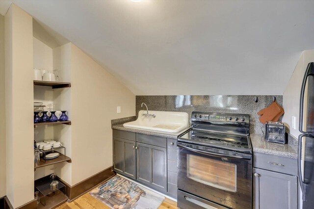 kitchen with light wood-type flooring, refrigerator, vaulted ceiling, sink, and black electric range