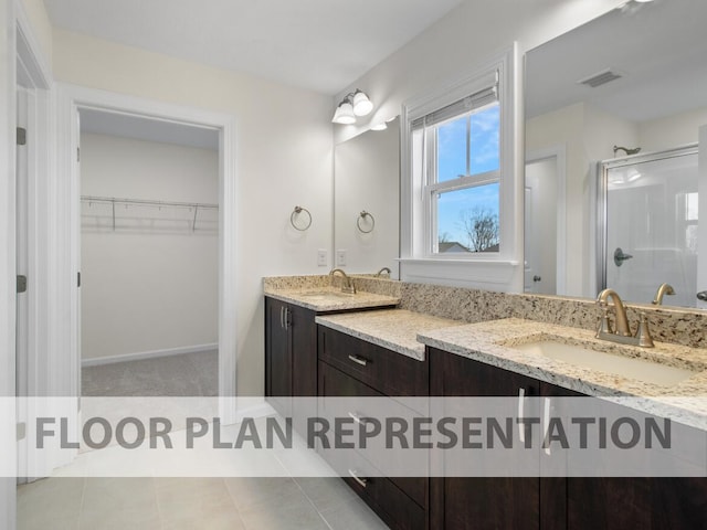 bathroom featuring a shower stall, a walk in closet, double vanity, and baseboards