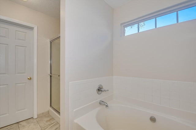 bathroom with a textured ceiling, plus walk in shower, and tile patterned floors