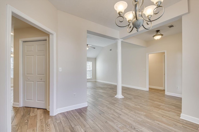 unfurnished dining area with light hardwood / wood-style floors, vaulted ceiling, decorative columns, and ceiling fan with notable chandelier