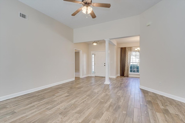 empty room featuring ceiling fan with notable chandelier, decorative columns, and light hardwood / wood-style floors