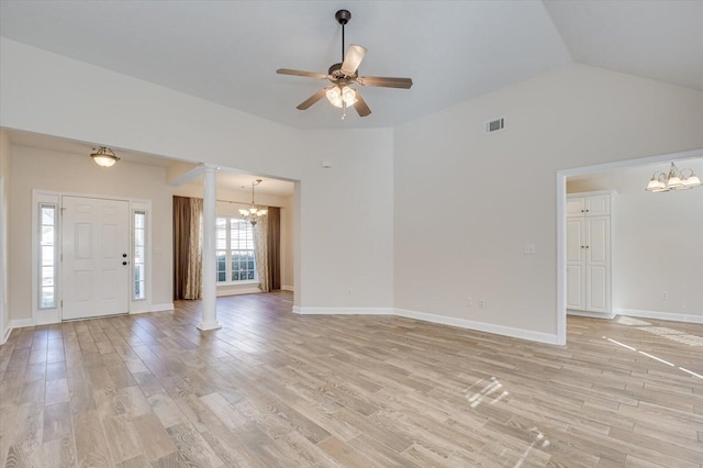 unfurnished living room with ceiling fan with notable chandelier, vaulted ceiling, decorative columns, and light hardwood / wood-style floors