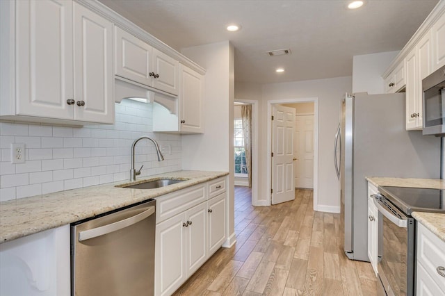 kitchen featuring light stone counters, white cabinets, appliances with stainless steel finishes, and sink