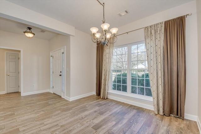 empty room with light hardwood / wood-style flooring and a chandelier