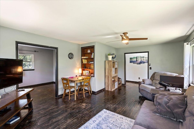 living room with ceiling fan, baseboards, and wood finished floors