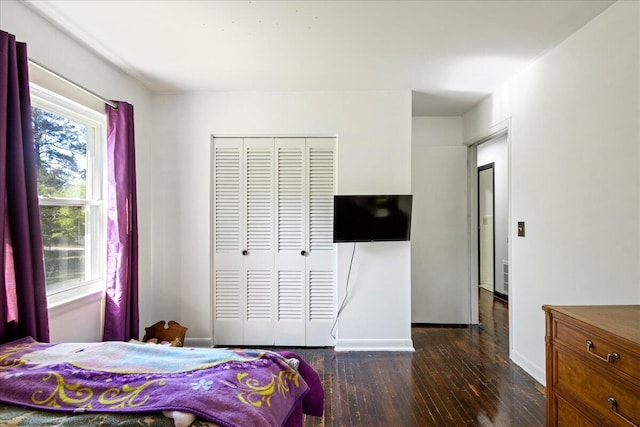bedroom with a closet, baseboards, and dark wood finished floors