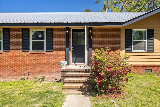 property entrance featuring brick siding, metal roof, and crawl space