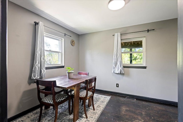 dining room featuring plenty of natural light, baseboards, and dark wood finished floors