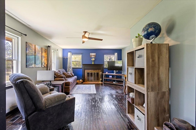 living room featuring wood finished floors, ceiling fan, and a fireplace
