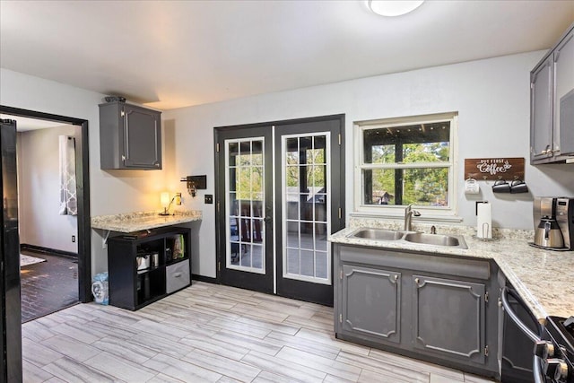 kitchen featuring black range oven, french doors, a sink, and wood finish floors