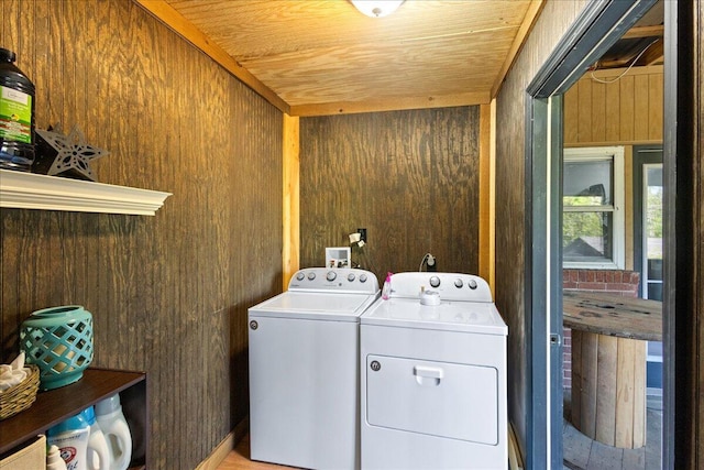 washroom with wooden walls, washing machine and clothes dryer, and laundry area
