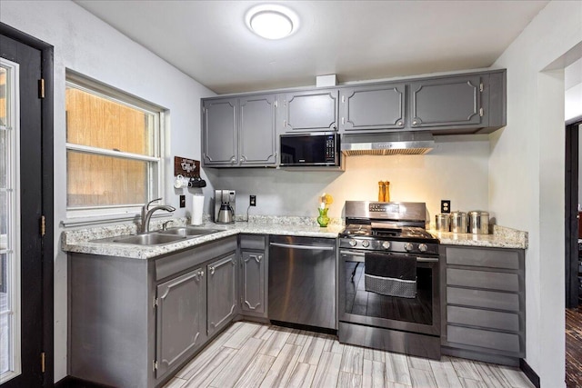kitchen with a sink, ventilation hood, gray cabinetry, and stainless steel appliances