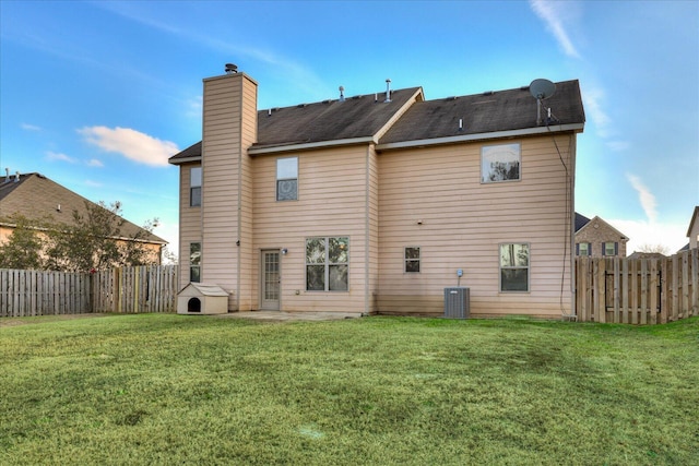 rear view of house with central AC unit and a yard