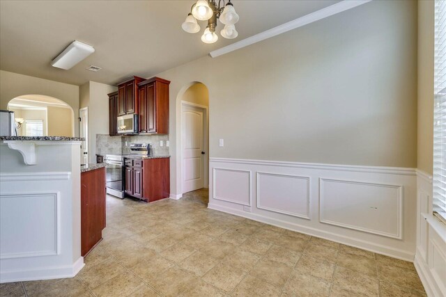 kitchen featuring a chandelier, appliances with stainless steel finishes, tasteful backsplash, and light stone counters