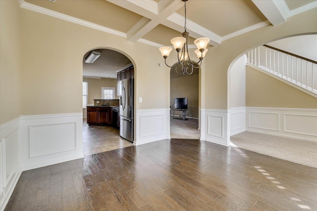 unfurnished dining area with beam ceiling, coffered ceiling, an inviting chandelier, wood-type flooring, and ornamental molding