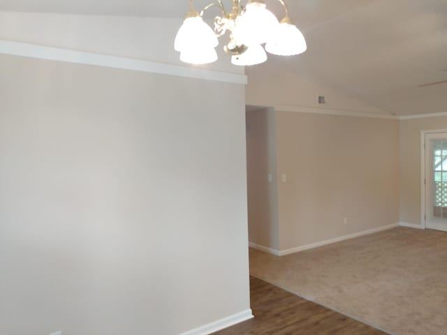 unfurnished room featuring wood-type flooring, ornamental molding, vaulted ceiling, and an inviting chandelier