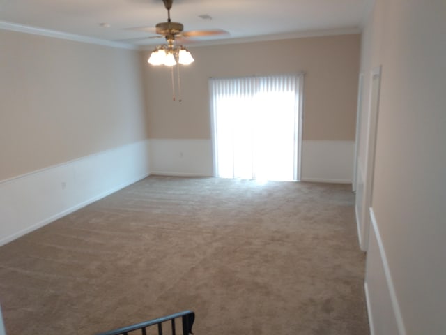 carpeted empty room with ceiling fan and ornamental molding