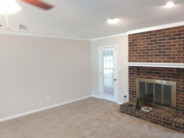 unfurnished living room featuring a textured ceiling, light colored carpet, a brick fireplace, and crown molding