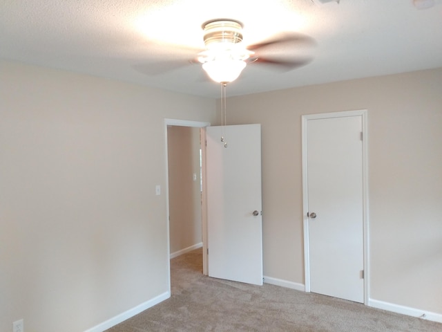 unfurnished bedroom with ceiling fan and light colored carpet