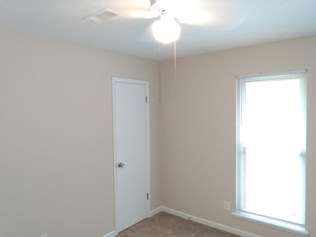 unfurnished room featuring carpet floors, a wealth of natural light, and ceiling fan