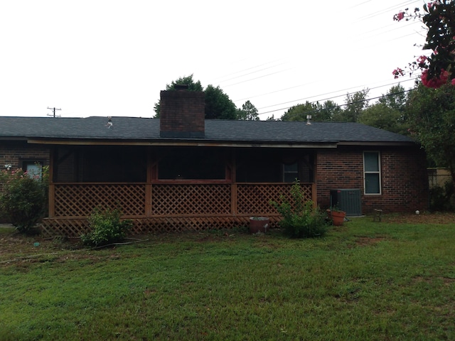 back of property with central AC unit and a lawn