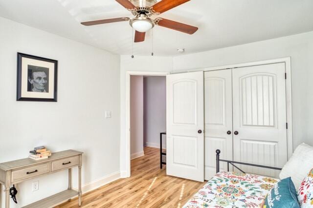 bedroom featuring a ceiling fan, a closet, light wood-style flooring, and baseboards