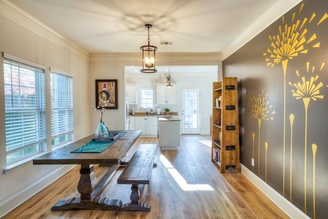 dining area featuring light wood-type flooring, visible vents, ornamental molding, and baseboards