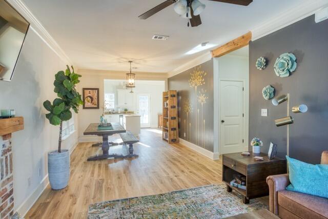 interior space featuring baseboards, visible vents, crown molding, and wood finished floors